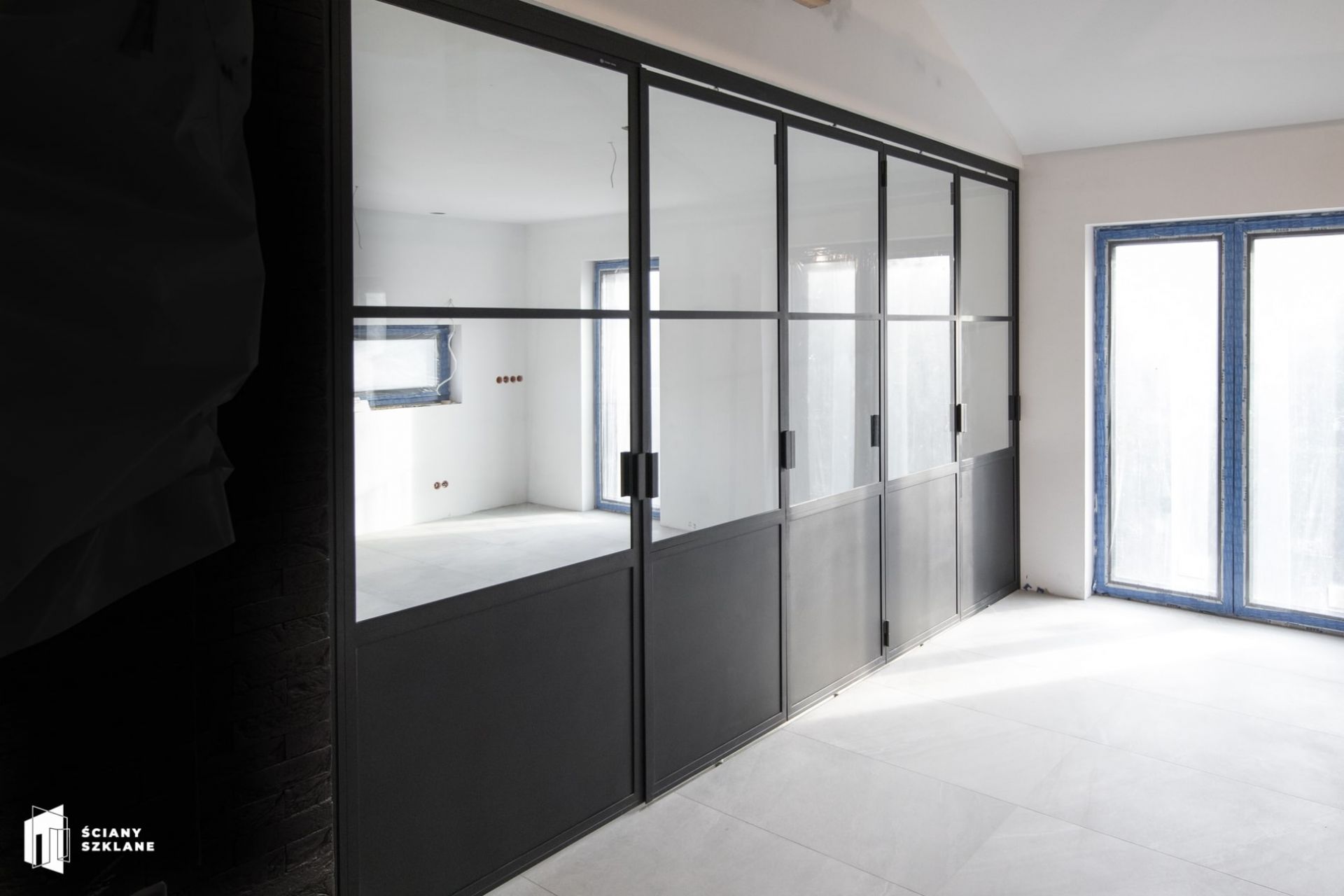 sciana oddzielajaca kuchnie od salonu, pojedyncze drzwi po lewej stronie, po prawej rozsuwane drzwi harmonijkowe, sciany-szklane.pl